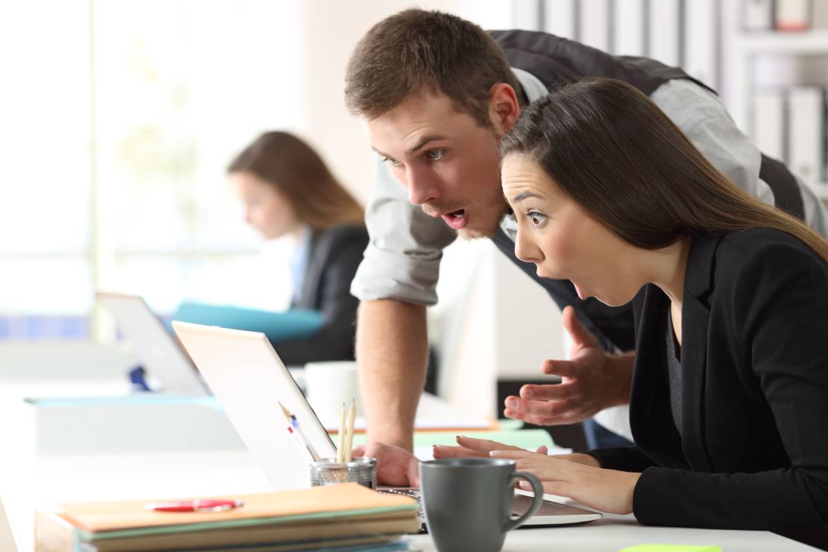 Excited man and woman reading from a laptop screen
