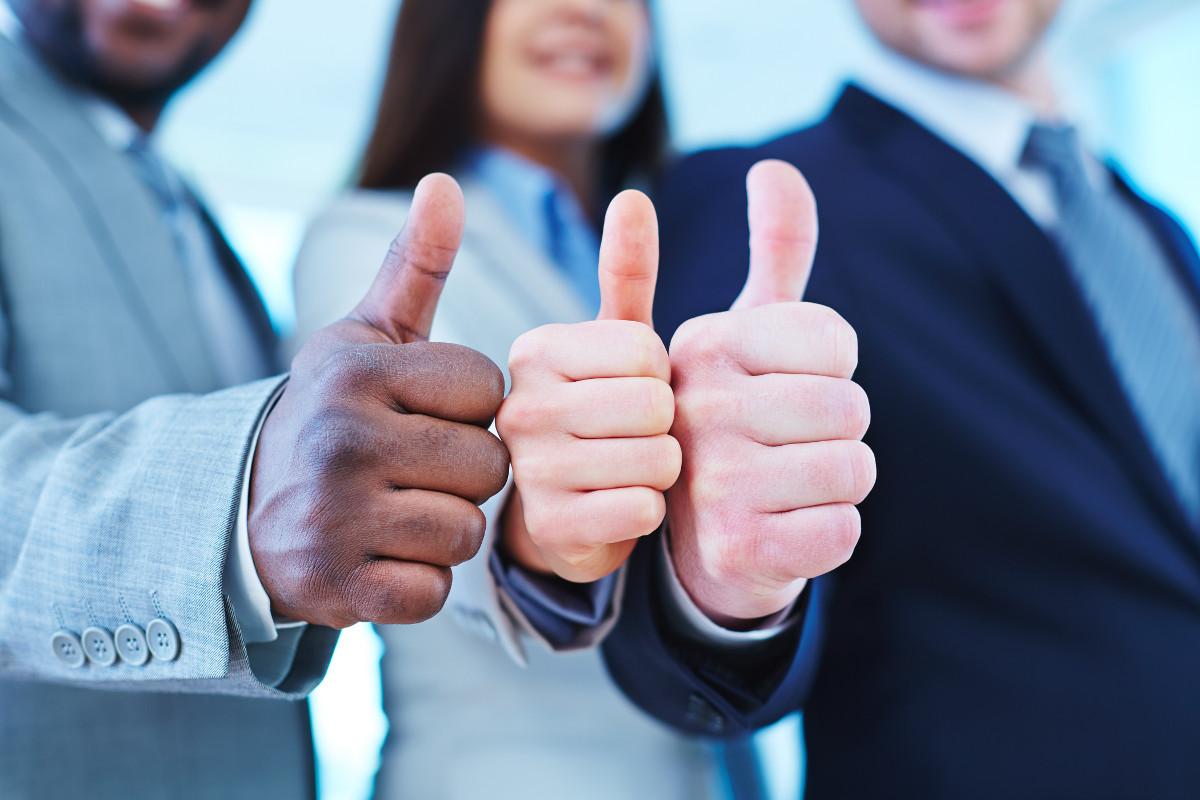 Three business people presenting a 'thumbs up' gesture.
